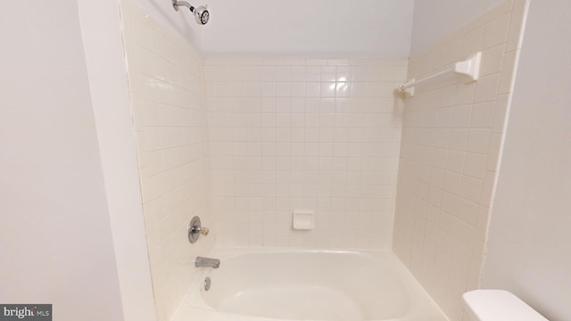 bathroom featuring toilet and tiled shower / bath