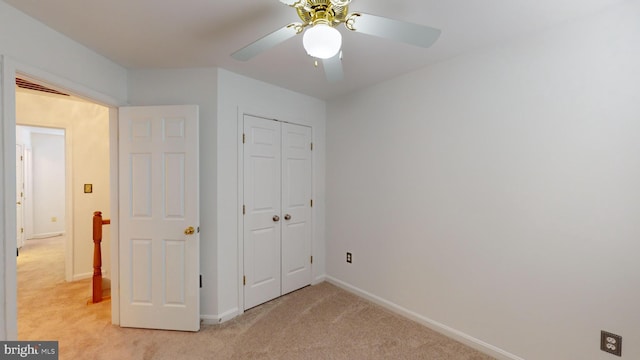 unfurnished bedroom with ceiling fan, light carpet, and a closet