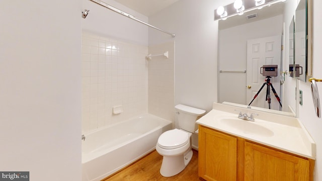 full bathroom featuring hardwood / wood-style floors, tiled shower / bath combo, toilet, and vanity