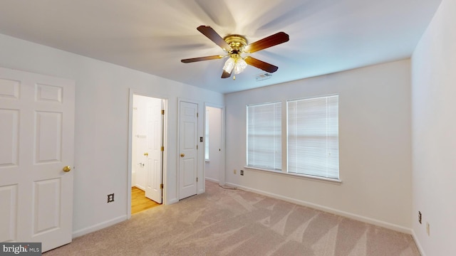 unfurnished bedroom featuring light carpet, ensuite bathroom, and ceiling fan