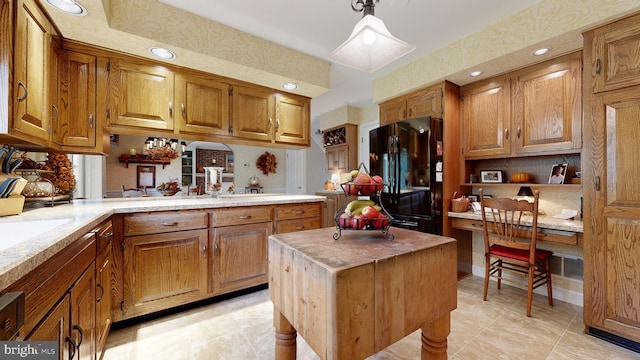 kitchen with black refrigerator, a center island, decorative light fixtures, and built in desk