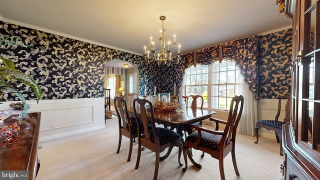 carpeted dining room with crown molding and a chandelier