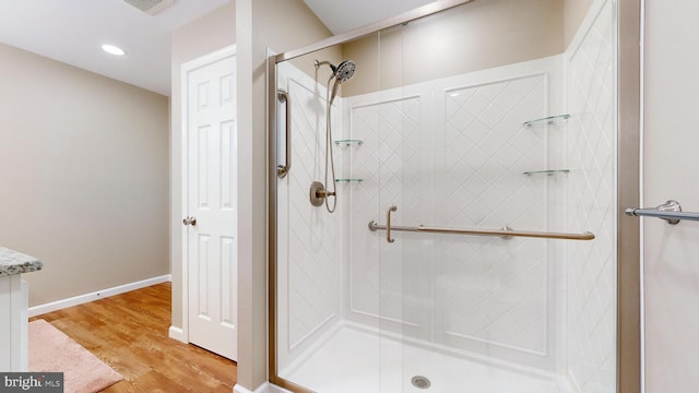 bathroom with a shower with door and hardwood / wood-style floors