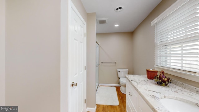 bathroom with vanity, hardwood / wood-style floors, a shower with door, and toilet