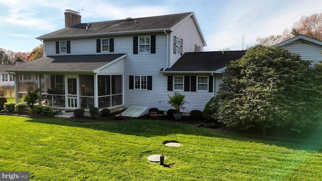 rear view of property featuring a sunroom and a lawn