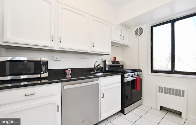 kitchen featuring white cabinetry, stainless steel appliances, radiator heating unit, and sink