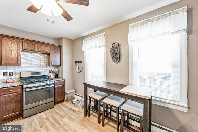 kitchen with plenty of natural light, gas stove, light hardwood / wood-style floors, and backsplash