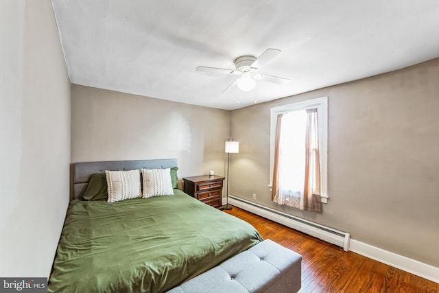 bedroom with ceiling fan, dark hardwood / wood-style flooring, and a baseboard heating unit