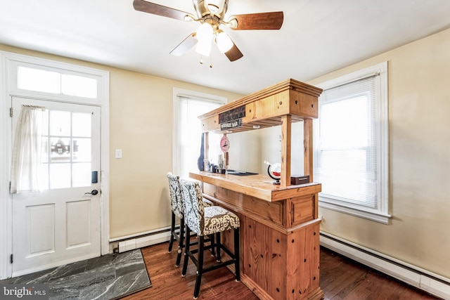 kitchen featuring baseboard heating, ceiling fan, dark hardwood / wood-style flooring, and a kitchen bar