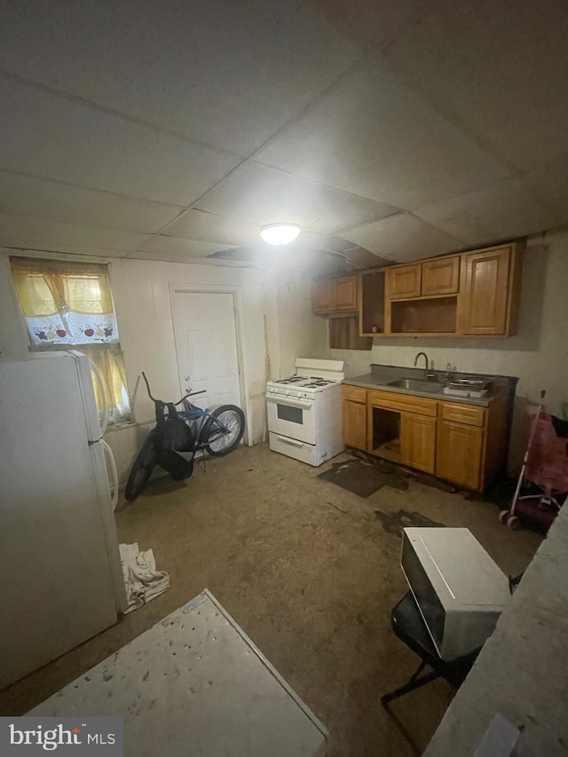 kitchen featuring white appliances, sink, and concrete flooring