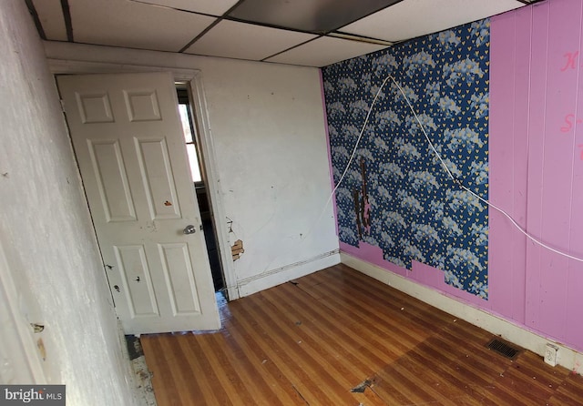 spare room featuring hardwood / wood-style floors and a drop ceiling