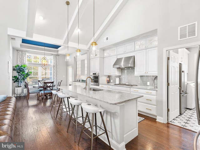 kitchen with a kitchen island with sink, white cabinetry, wall chimney exhaust hood, and pendant lighting