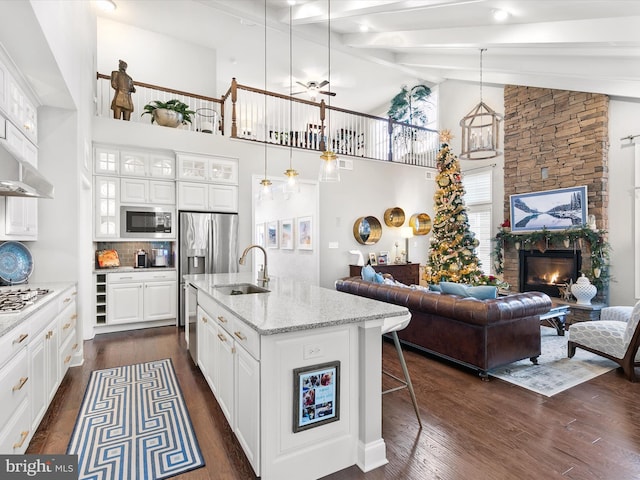 kitchen with an island with sink, stainless steel appliances, white cabinetry, and sink