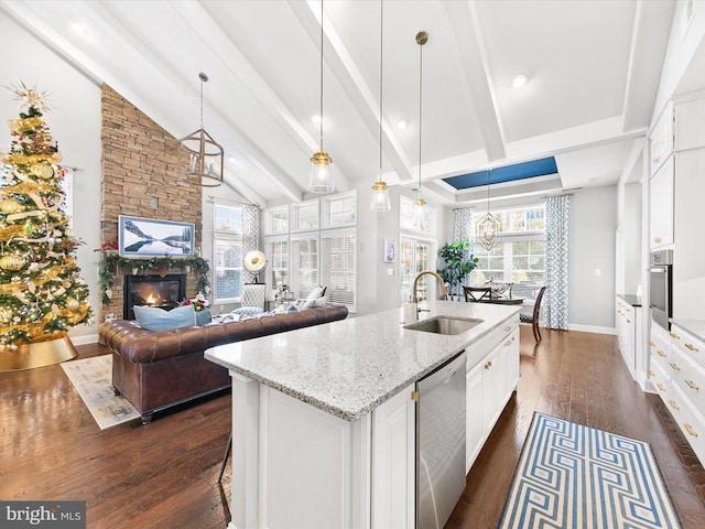 kitchen featuring a stone fireplace, sink, dark hardwood / wood-style floors, appliances with stainless steel finishes, and white cabinetry