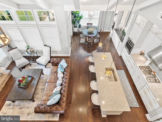 living room with plenty of natural light, beam ceiling, dark hardwood / wood-style flooring, and a chandelier