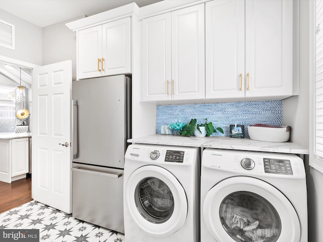 clothes washing area featuring cabinets and washing machine and clothes dryer