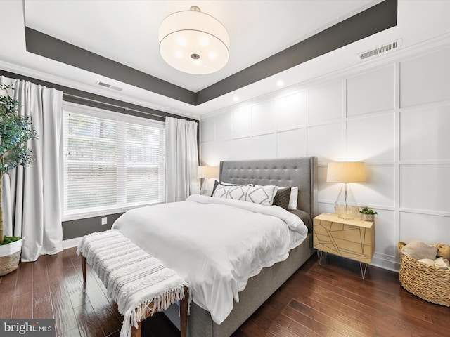 bedroom featuring a raised ceiling and dark wood-type flooring