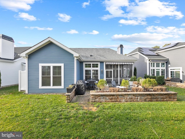 rear view of house with a yard, a patio area, and a sunroom