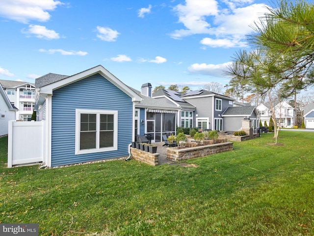 back of house featuring a sunroom and a lawn