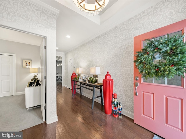 foyer entrance with a notable chandelier, dark hardwood / wood-style flooring, and ornamental molding