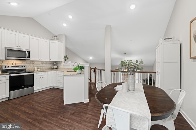 kitchen featuring appliances with stainless steel finishes, vaulted ceiling, sink, white cabinets, and dark hardwood / wood-style floors