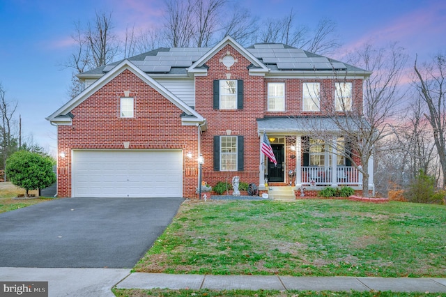 view of front of house featuring solar panels, a porch, a garage, and a lawn