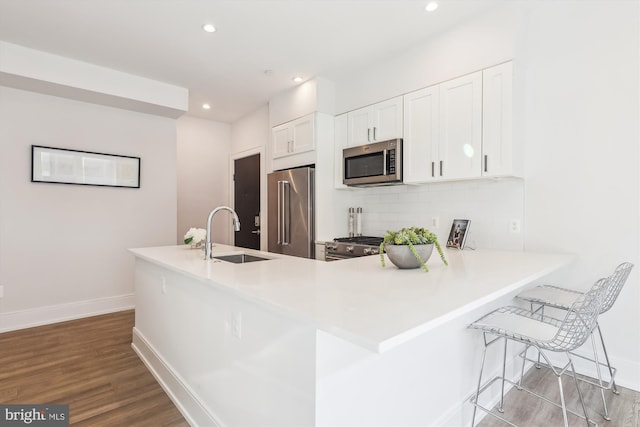 kitchen with high end appliances, white cabinetry, sink, kitchen peninsula, and light wood-type flooring