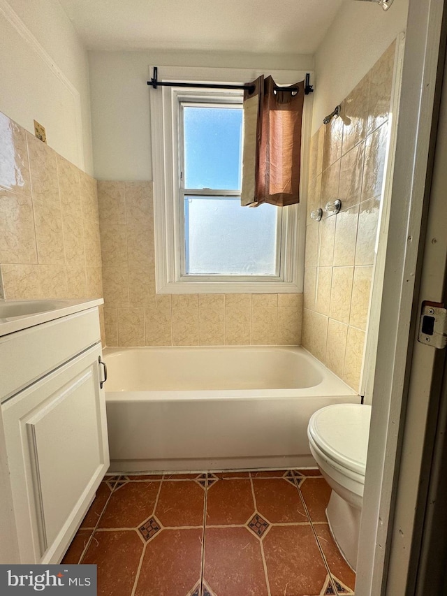 bathroom with tile patterned flooring, toilet, a bathtub, vanity, and tile walls