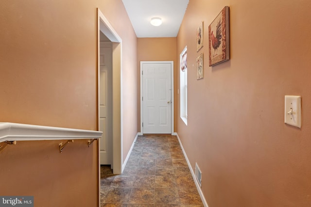 corridor with stone finish floor, visible vents, and baseboards