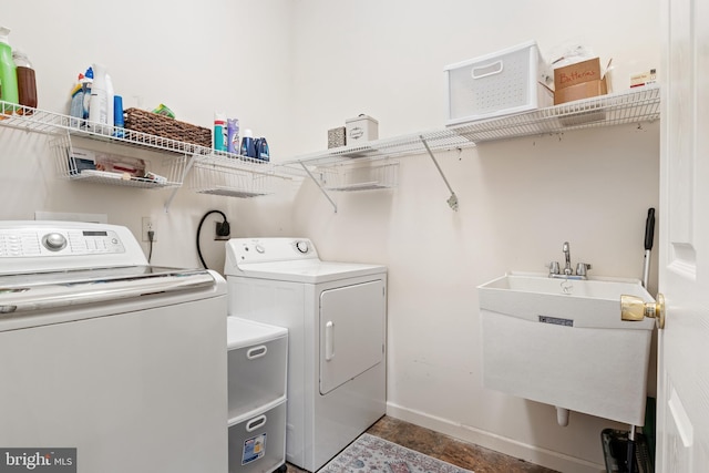 washroom with laundry area, washing machine and dryer, baseboards, and a sink