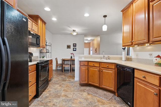 kitchen with brown cabinets, a peninsula, light countertops, black appliances, and a sink