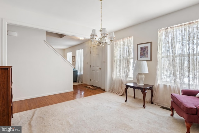 sitting room with baseboards, visible vents, wood finished floors, an inviting chandelier, and carpet floors