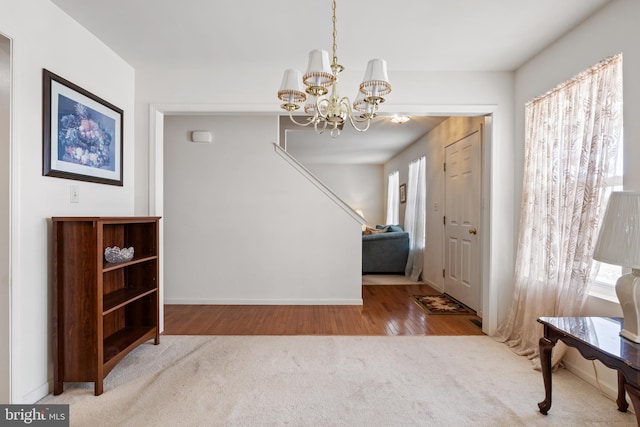 foyer entrance with carpet floors, plenty of natural light, baseboards, and a notable chandelier