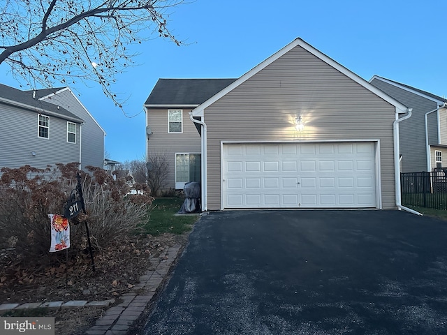 view of front facade with aphalt driveway, an attached garage, and fence