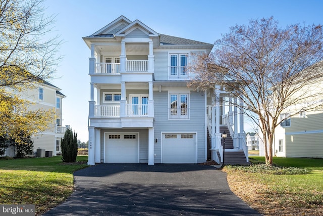 view of front of house featuring a front lawn, a garage, a balcony, and central AC