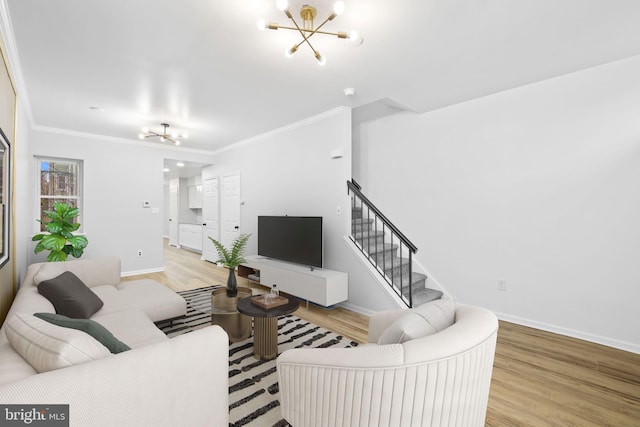 living room with a notable chandelier, light hardwood / wood-style floors, and ornamental molding