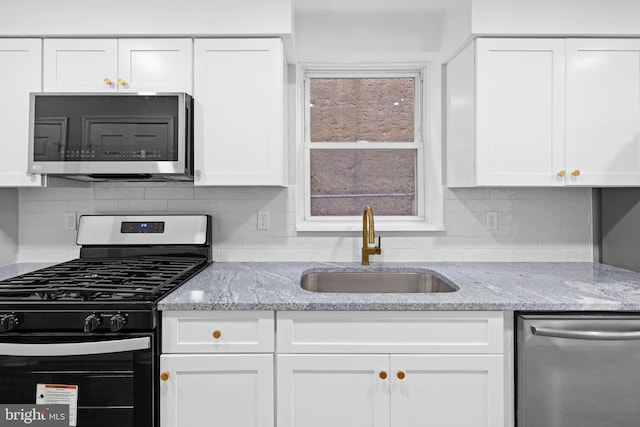 kitchen with light stone countertops, sink, white cabinets, and appliances with stainless steel finishes