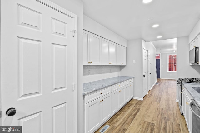 kitchen featuring light stone counters, light hardwood / wood-style flooring, white cabinets, and stainless steel appliances