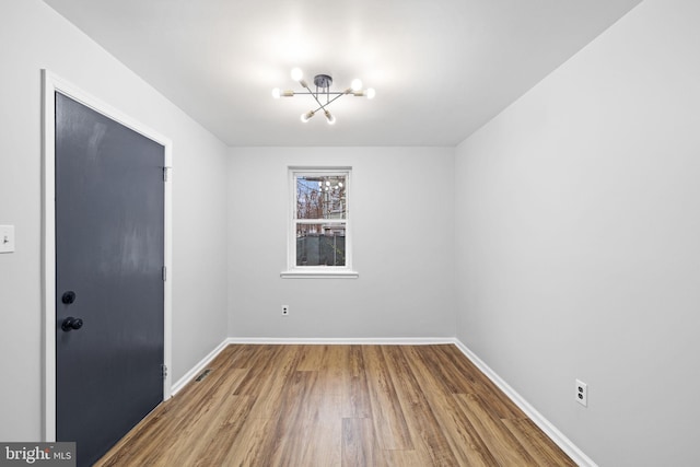 empty room featuring hardwood / wood-style flooring and a notable chandelier