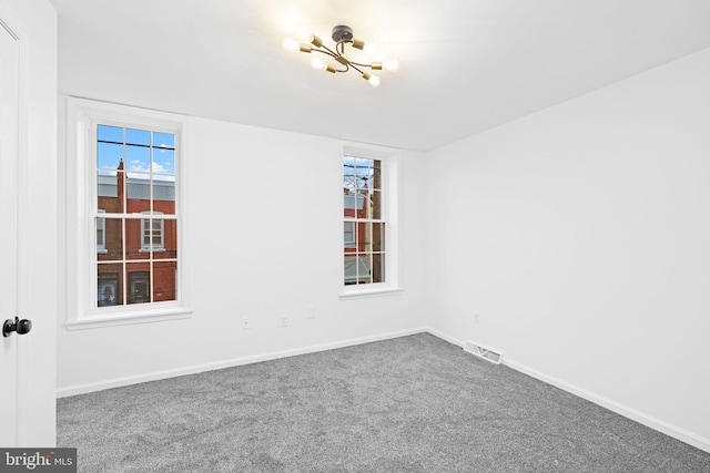 empty room featuring carpet flooring and a chandelier