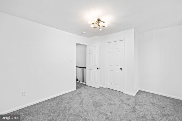 empty room featuring carpet and a chandelier