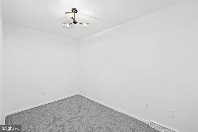 carpeted spare room featuring a chandelier