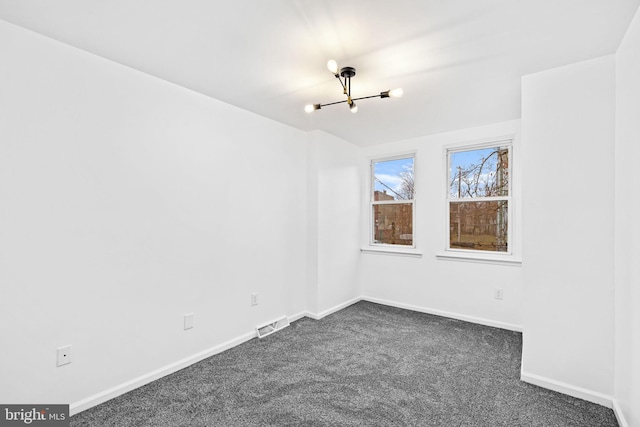 carpeted spare room with an inviting chandelier