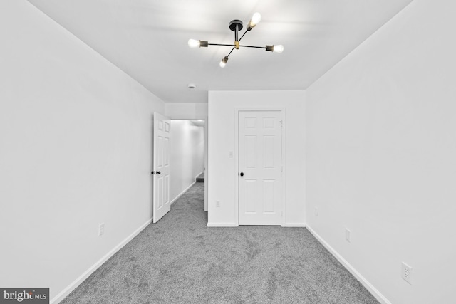 unfurnished bedroom with carpet floors and a chandelier