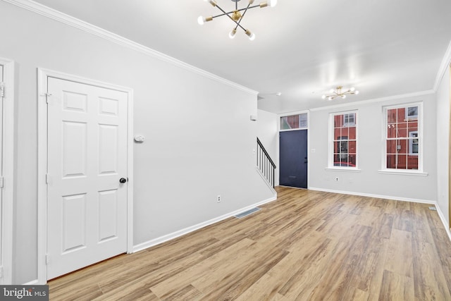 unfurnished room featuring light wood-type flooring, ornamental molding, and an inviting chandelier