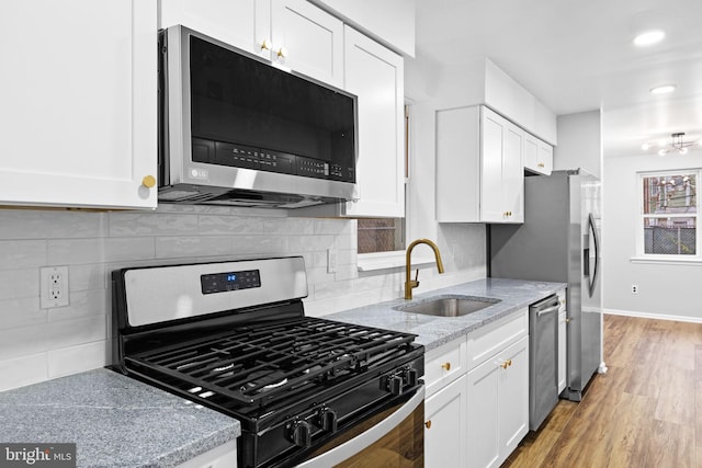 kitchen featuring backsplash, white cabinetry, sink, and stainless steel appliances