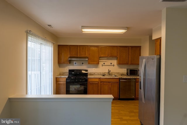 kitchen featuring sink, stainless steel appliances, light hardwood / wood-style flooring, backsplash, and kitchen peninsula