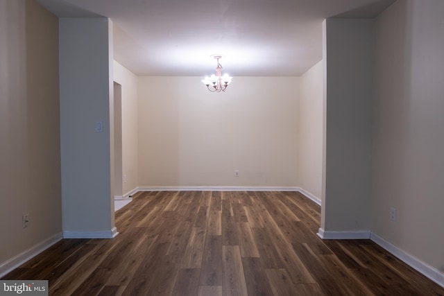 unfurnished room featuring dark hardwood / wood-style flooring and an inviting chandelier