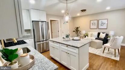 kitchen featuring stainless steel fridge, a center island, and white cabinetry