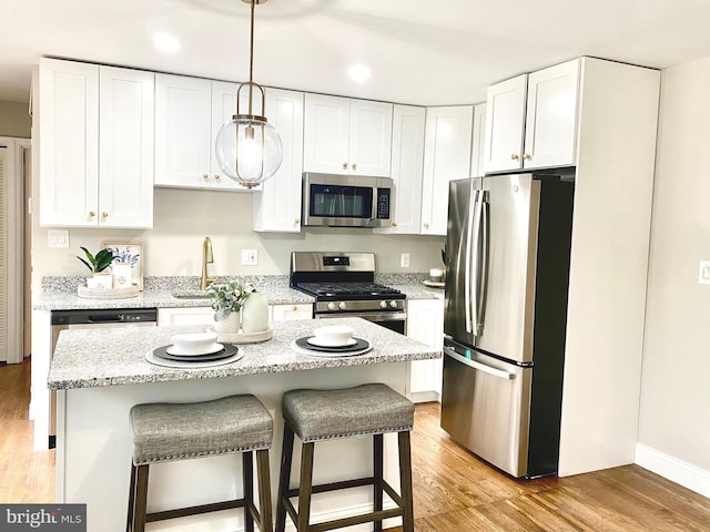 kitchen featuring pendant lighting, a center island, white cabinets, light wood-type flooring, and appliances with stainless steel finishes